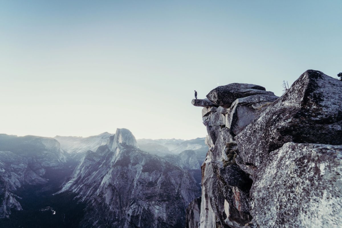 potential risk: man sitting on mountain ledge