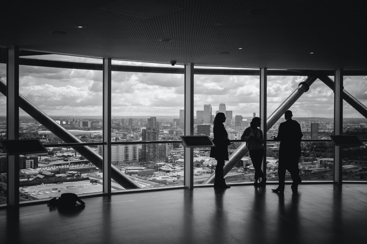 internal succession deals: 3 business people standing in an office with large windows