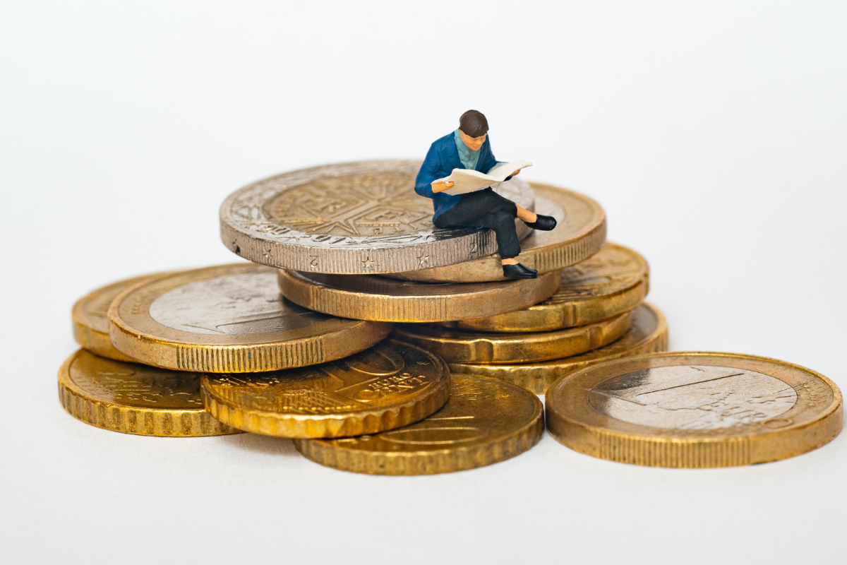 angel investing: man sitting on a pile of large gold coins