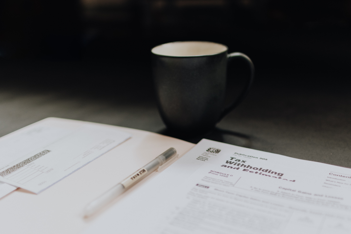 capital gains rates: black coffee mug sitting next to a legal folder with a paper reading "tax withholdings"