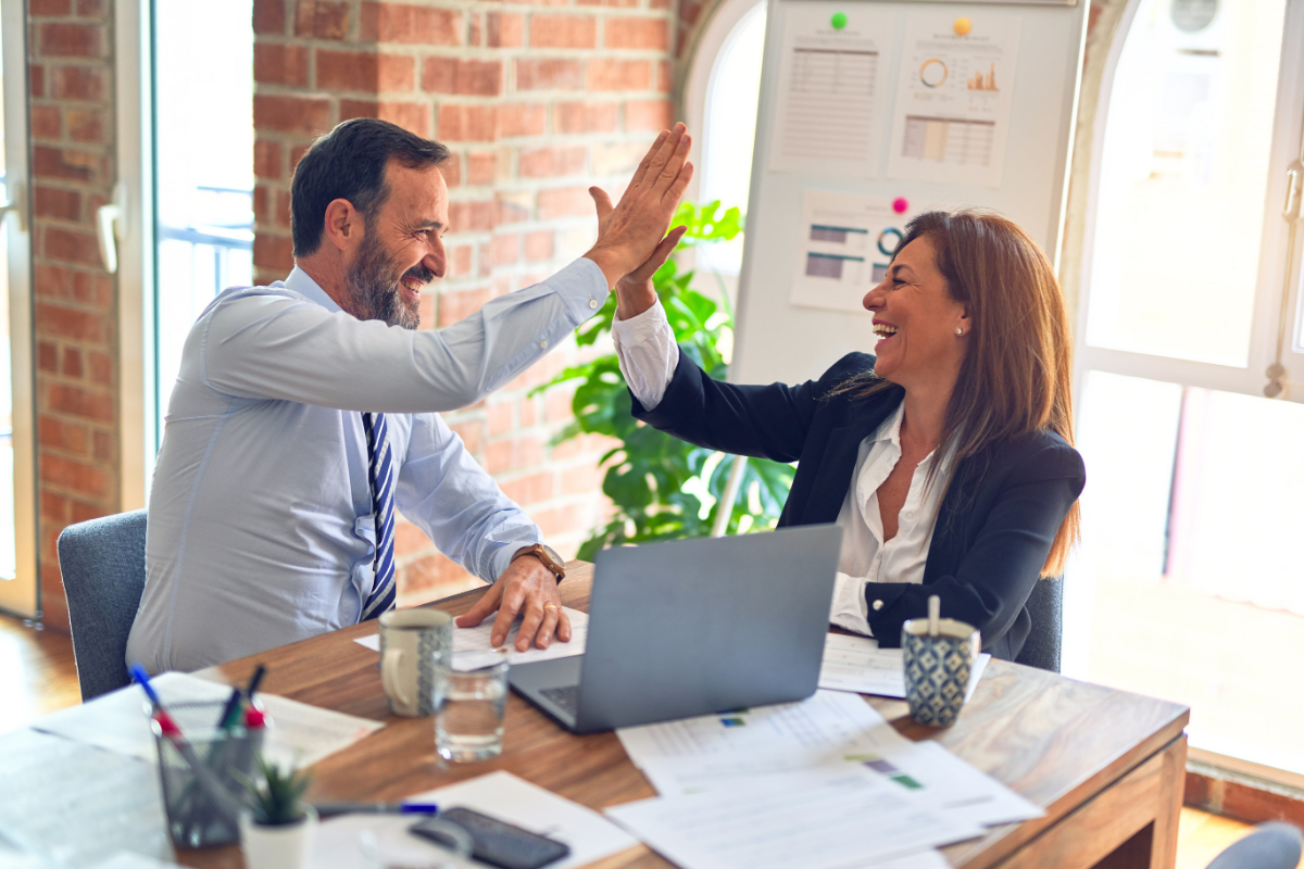 asset management: a man and a woman dressed in business clothing giving one another a high five