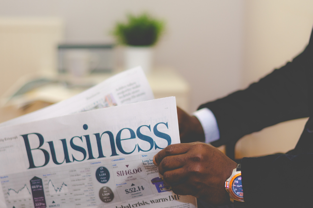 coaches: mans hands holding a business newspaper. Wearing a suit and gold watch.