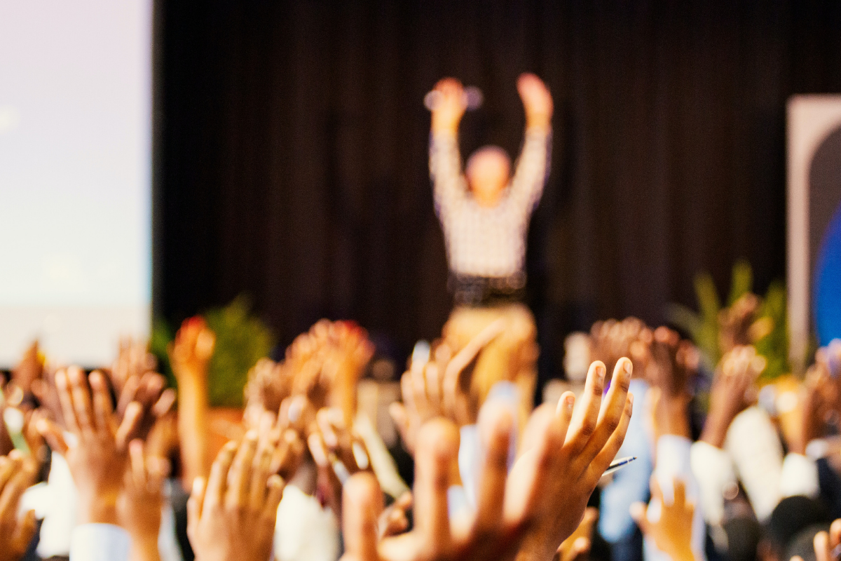 speaker management: a female speaker on stage, raised hands in the audience