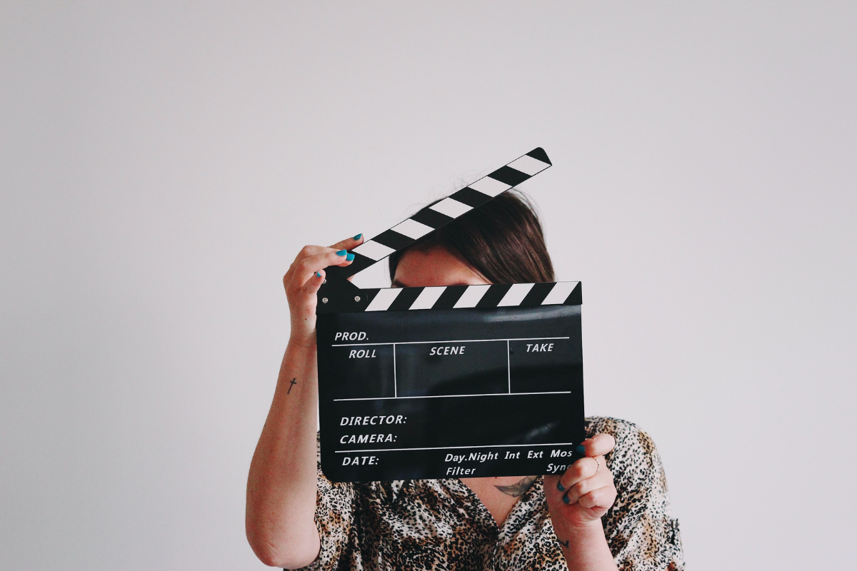 Deal-Making Like a Producer: Woman holding a clapperboard in front of her face.