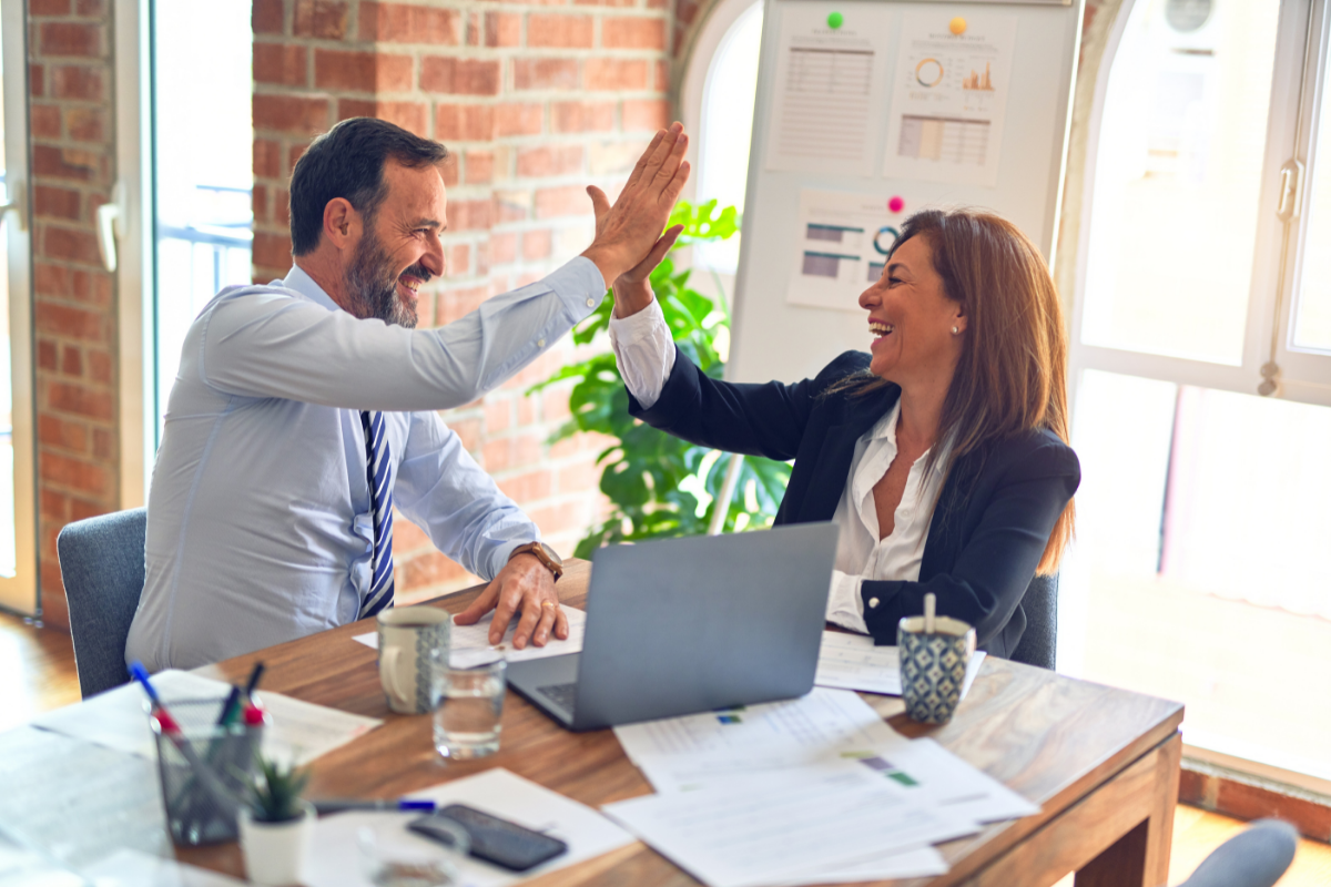 deal-making salesman: a man and woman wearing business clothes and high fiving